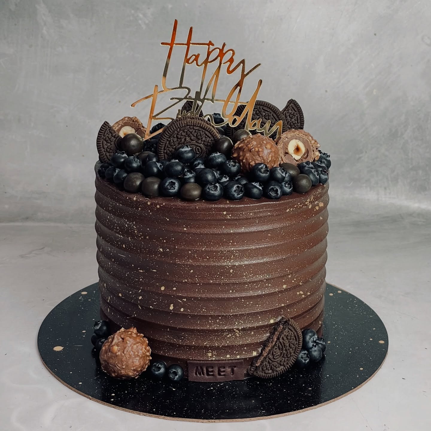 Chocolate birthday cake decorated with berries and cookies