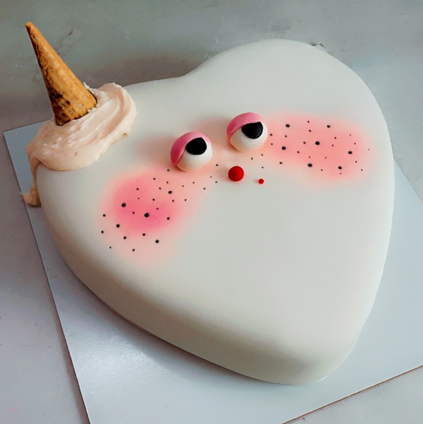 Whimsical white fondant cake with a playful face
